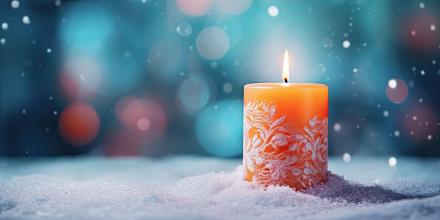 Brennende orangefarbene Kerze mit winterlichem Muster steht auf Schnee, im Hintergrund bunte Lichter und sanft fallende Schneeflocken – stimmungsvolle Winter- oder Weihnachtsatmosphäre